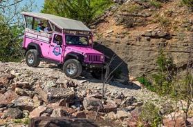 �Pink off-road Jeep navigating a rocky Ozark trail, representing outdoor adventures offered among Branson Museum and Attractions.�