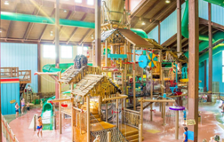 Children playing in a bright indoor water park filled with slides and water features,